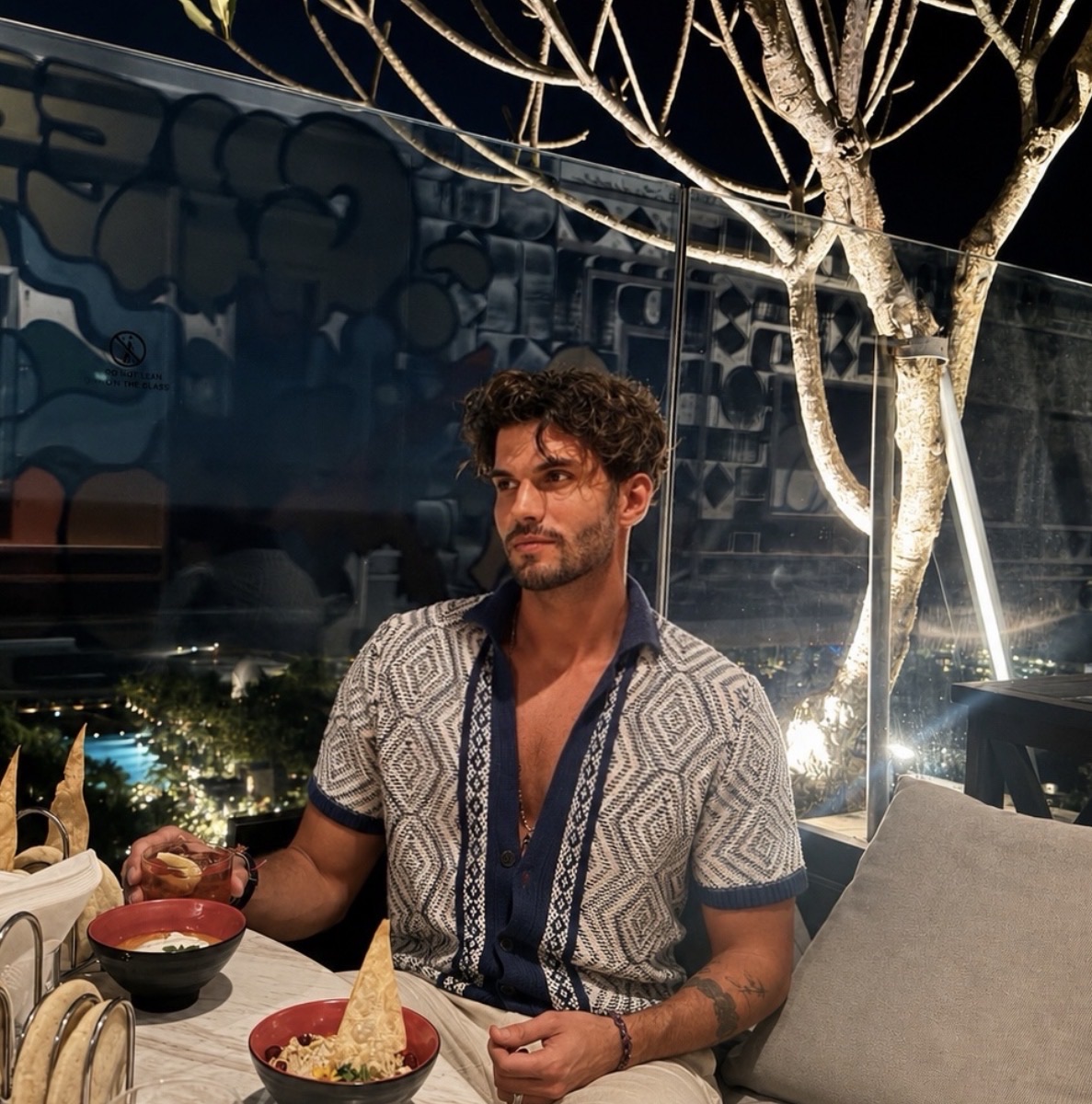 Moritz Denninger am Abend auf einer Dachterrasse, lächelnd im gemusterten Hemd